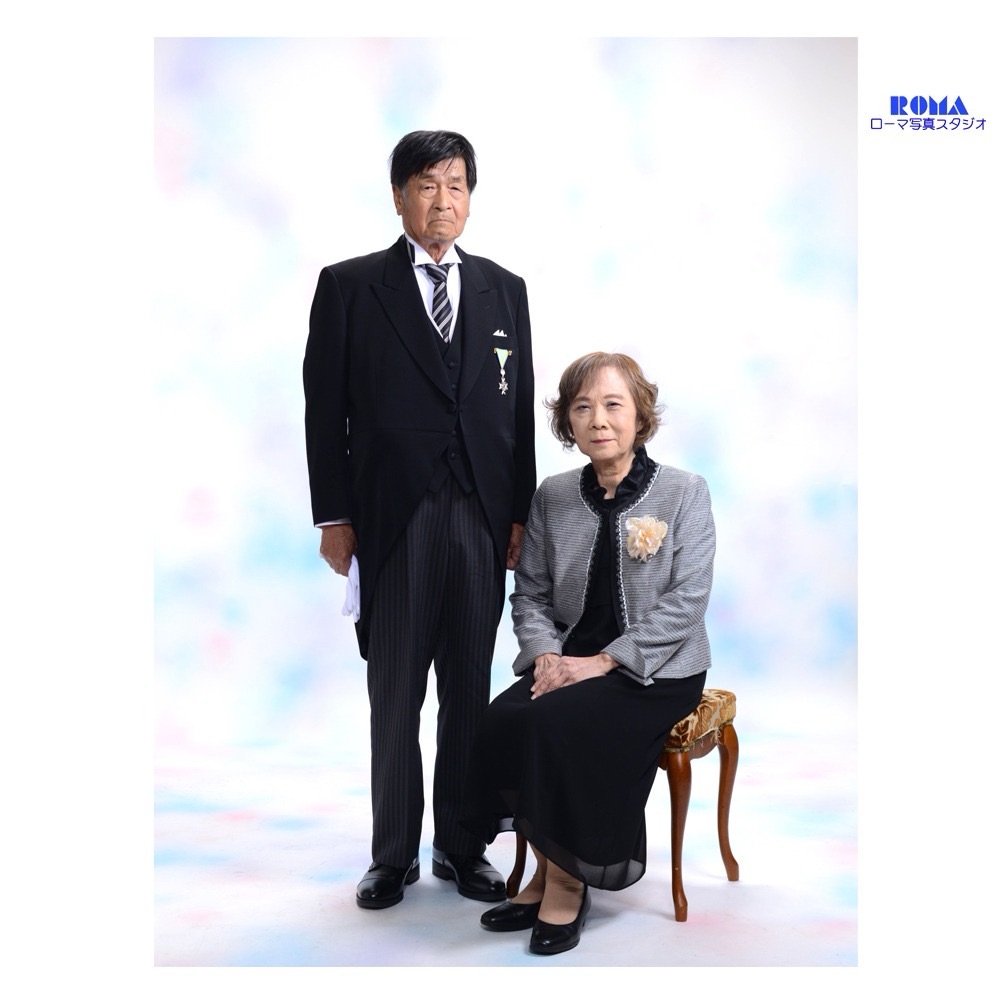 静岡で叙勲を祝うご夫婦の記念写真。モーニング姿のご主人とコサージュをつけた奥様